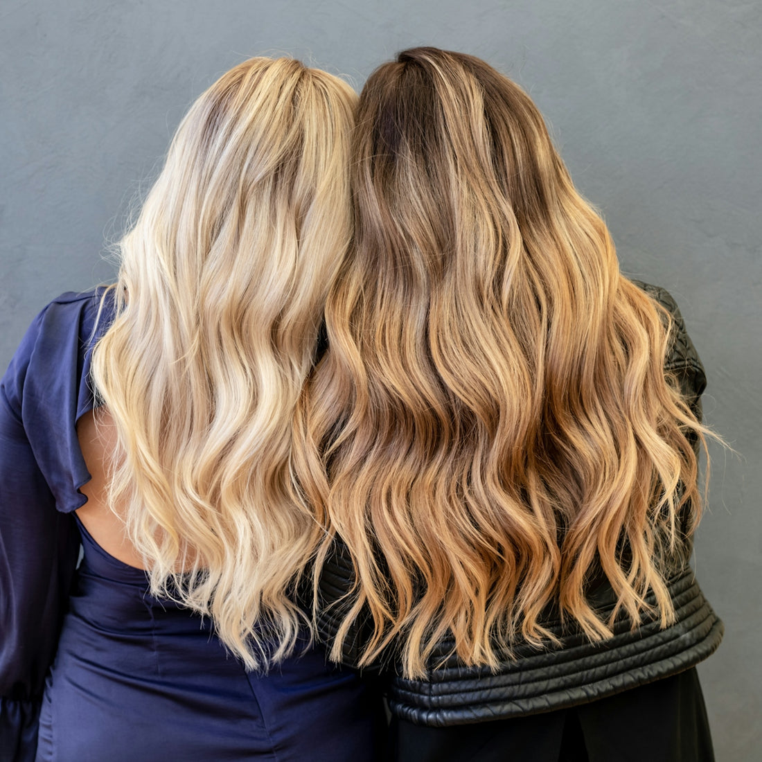 Two women with long, wavy blonde and brunette hair